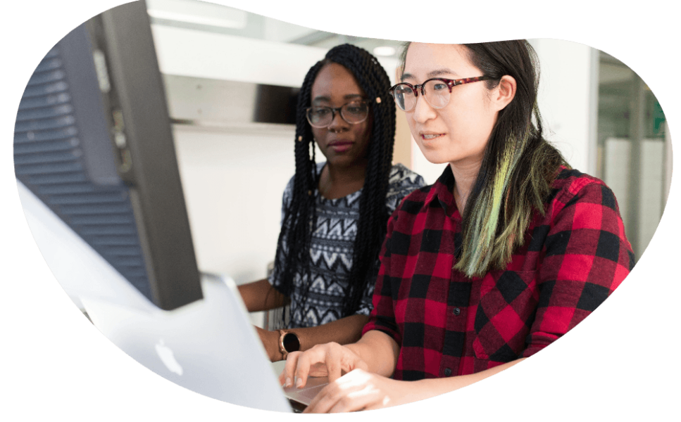 Two women sat working on a computer.
